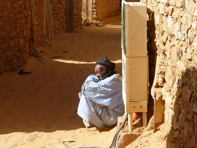 Man sitting by street side - old town