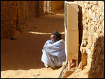 Man sitting by street side - old town