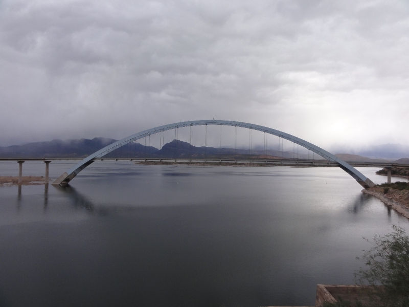 DSC02295.JPG - Roosevelt Dam Bridge on Roosevelt Lake just east of Roosevelt Dam.  It was drizzling and made for a dreamy atmosphere.  Prior to completion of the bridge in October 1990, traffic drove over the top of the dam. The bridge itself earned rare distinction when the bridge was named one of the top 12 bridges in the nation in November 1995. The American Consulting Engineers Council cited the bridge for overall design, size, eye-appeal and design challenge. Other bridges cited were the Golden Gate Bridge and Brooklyn Bridge.