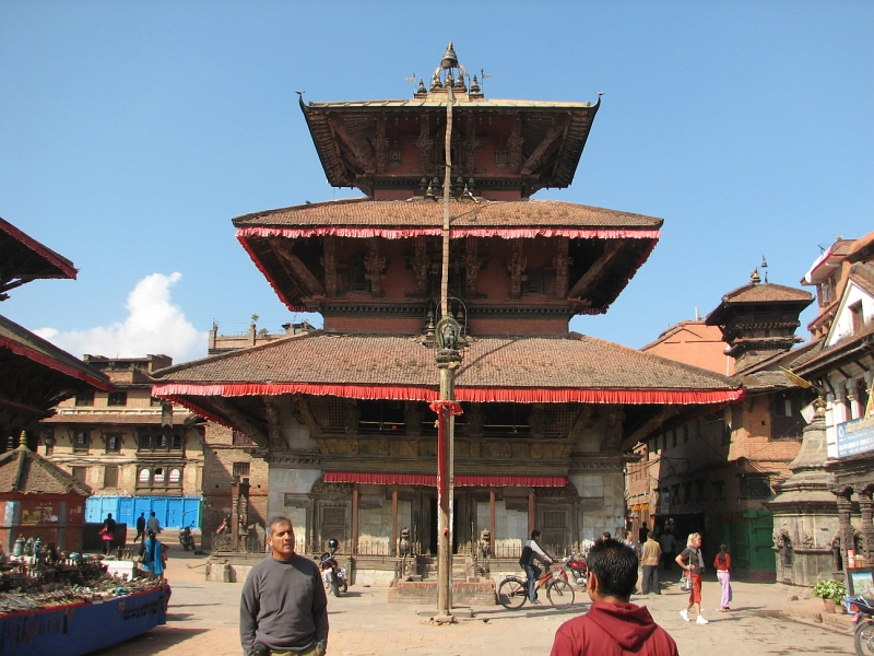 IMG_8475.JPG - At the northern end of Durbar Square, the Bhimsen Temple is dedicated to the god of trade and business. Although it is not known when it was first built, an inscription records that it was rebuilt in 1682 after a fire.  A lion tops a pillar in front of the temple. Thle the brick building has an artificial marble facade and a gilded facade on the first floor.