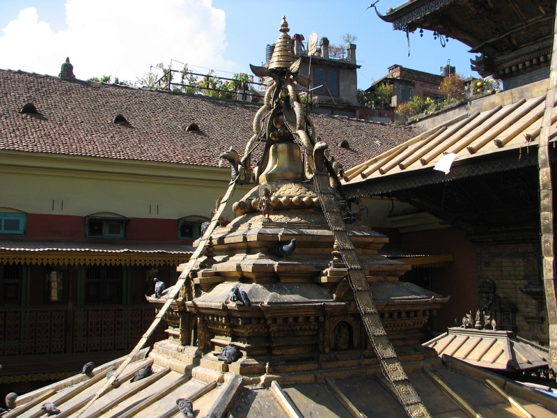 IMG_8485.JPG - In the center is a small, richly decorated temple with a golden roof that has an extremely ornate bell shaped top. Inside iin the oldest part of the temple is a 'self-arisen' (swayambhu) chaitya